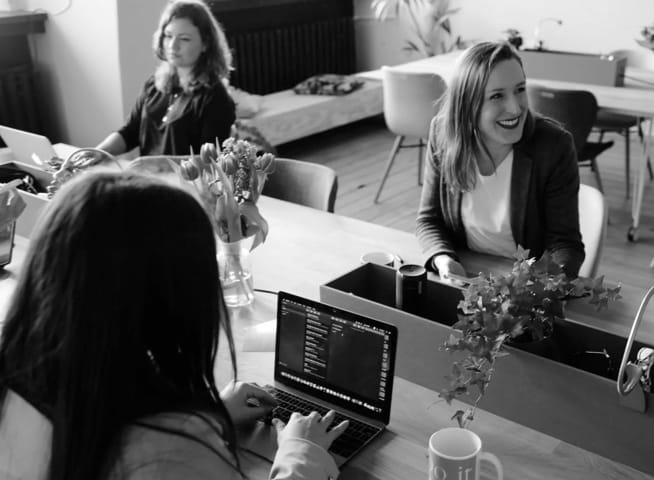 women working on laptops sitting around a table